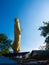 Large golden Buddha in the middle of the market, sunny blue sky.