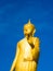 Large golden Buddha in the middle of the market, sunny blue sky.