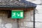 Large green emergency exit sign fixed under a tiled roof, castle entrance, safety for all visitors, during the day without people