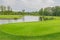 A large green field, meadow. Lake and trees