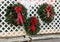 Large green wreaths with red ribbons and baubles on section of white lattice