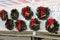 Large green wreaths with red ribbons and baubles on section of white lattice