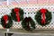 Large green wreaths with red ribbons on section of white lattice