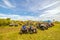 a large group of ATVs stand in the background against the blue sky on a summer sunny day. Russian fans of pokatushek gathered in