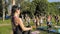 A large group of children engaged in yoga in the park sitting on the grass