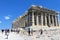 A large group of visitors admiring the Parthenon atop the Acropolis on a hot sunny day during a summer day in Athens