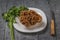 A large gyromitra mushroom on a white plate with parsley leaves and a knife on a wooden table.