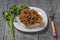 A large gyromitra on a white plate with a fork and herbs.