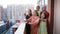 A large happy family of five people on the balcony of a new residential complex enjoy the view of the neighborhood.