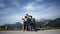 Large happy family of five-person travelers enjoy stunning mountain views from the side of the road. European Alps