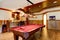 Large hardwood floor room with pool table and bar.