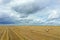 Large harvesting field of wheat and bales of hay