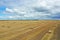 Large harvesting field of wheat and bales of hay