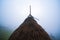 A large haystack stands on a green field among the dense gray fog