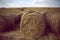 Large haystacks stand in a mowed field at sunset