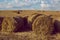 Large haystacks stand in a mowed field at sunset