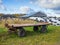 Large heap of silage as animal fodder covered in tires and white plastic and agricultural trailer, farm in North Germany