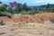 Large heaps of brown clay and earth in a thicket overgrown with green vegetation