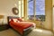 Large high ceiling bedroom with red bed.