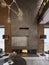 Large high concrete fireplace with built-in firebox with burning fire. Two black floor lamps