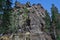 Large high rough climbing rock Vityaz in Siberian forest with conifers in winter in the light of sun. People climbers on big cliff