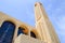 large high tower, a spire in an Egyptian orthodox white church with crosses, arches, domes and prayer windows against the blue sk