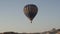Large hot air balloon with tourists flies over hills