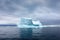 large iceberg floating in open sea under a precipitating sky