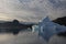 A large iceberg looms in the foreground with high wispy clouds and mountains in the background in northwest Greenland