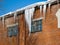 A large icicle hangs from the roof of an old industrial building