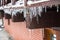 Large icicles on the roof of a wooden house on a snowy day