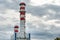 A large industrial smokestack against a blue sky. Red and white pipe in commercial enterprises or power plants