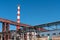 A large industrial smokestack against a blue sky. Red and white pipe in commercial enterprises or power plants