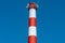 A large industrial smokestack against a blue sky. Red and white pipe in commercial enterprises or power plants