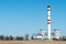 A large industrial smokestack against a blue sky. Red and white pipe in commercial enterprises or power plants