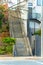 Large industrial staircase with cement steps and gray metal hand rails with trees on side and buildings