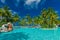 Large infinity swimming pool on the tropical beach with palm tre