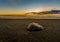 Large isolated black stone in the middle of the black sand beach of Reynisfjara illuminated by the last rays of sunset sun from