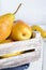 Large juicy yellow pears in a rustic wooden fruit box on a white table