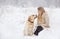 A large labrador dog and a cat in winter on a walk with a young woman in a snowy field