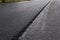 A large layer of fresh hot asphalt. Layer of asphalt raw material in a shallow depth of field. Rollers rollin fresh hot