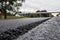 A large layer of fresh hot asphalt. Layer of asphalt raw material in a shallow depth of field. Rollers rollin fresh hot