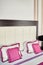 Large leather headboard of luxury bed, white and pink pillows on it, copy space. Feminine bedroom. Checkered soft headboard
