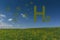 large letters with grass hydrogen h2 on blue sky and green spots