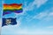 large lgbt flag and flag of Connecticut state, USA waving in the wind at cloudy sky. Freedom and love concept. Pride month.