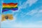 large lgbt flag and flag of New Jersey state, USA waving in the wind at cloudy sky. Freedom and love concept. Pride month.