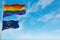 large lgbt flag and flag of North Dakota state, USA waving in the wind at cloudy sky. Freedom and love concept. Pride month.