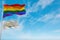large lgbt flag and flag of Rhode Island state, USA waving in the wind at cloudy sky. Freedom and love concept. Pride month.