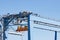 Large lifting structures with suspended spreader for cargo containers on the background of the blue sky