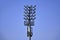 Large lighting tower with spotlights and loudspeakers installed against bright blue cloudless sky.